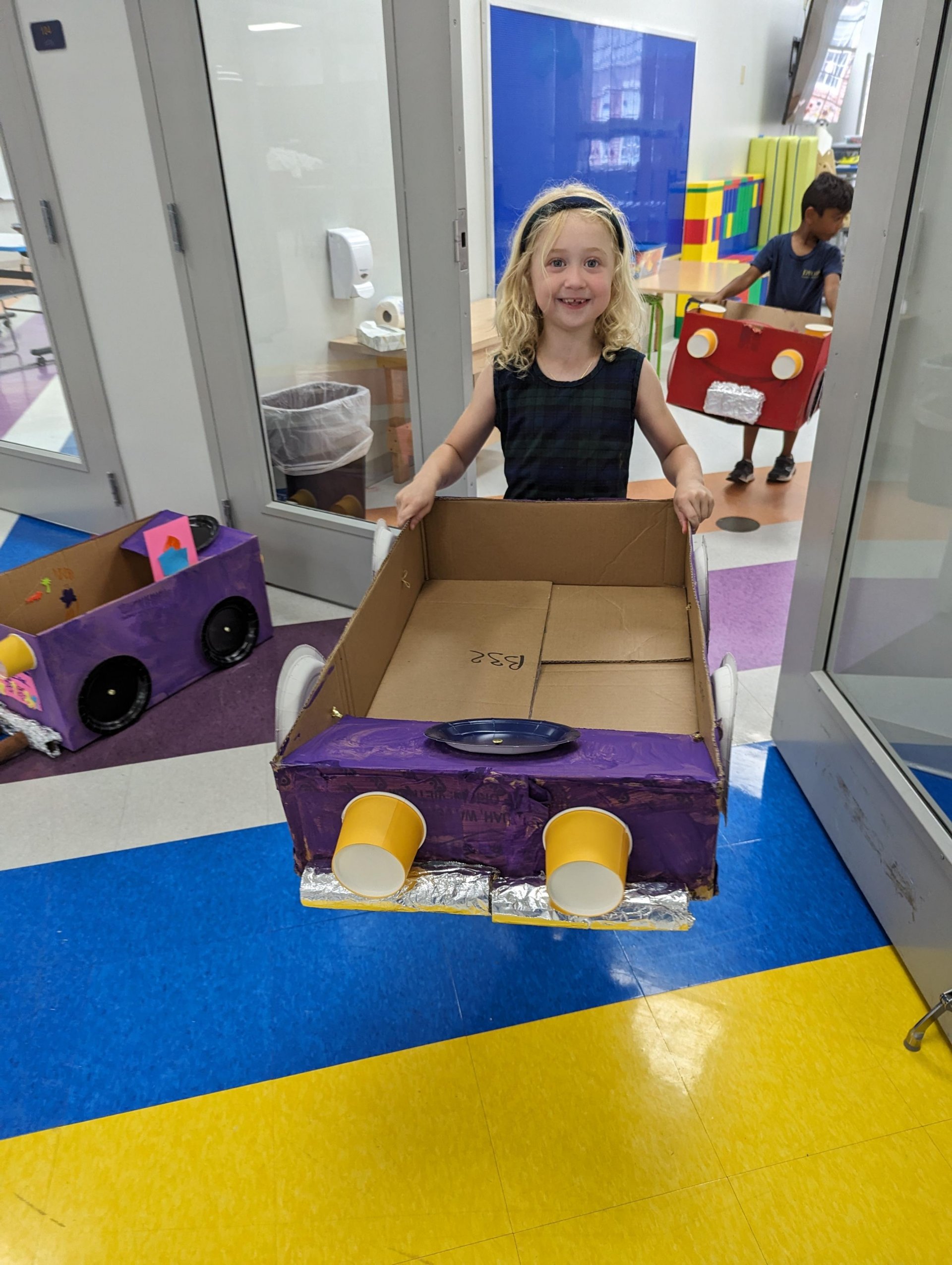 Kindergarten student with cardboard car