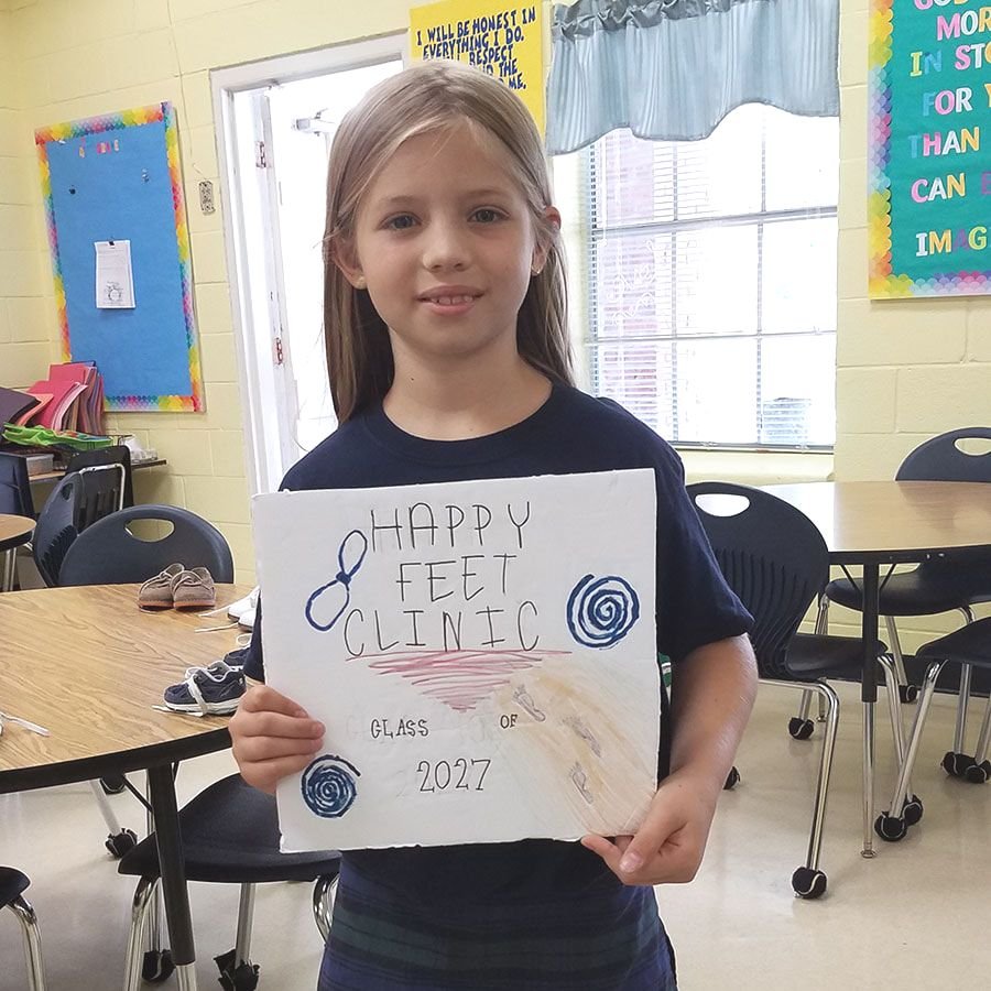Student with the Happy Feet  Clinic sign
